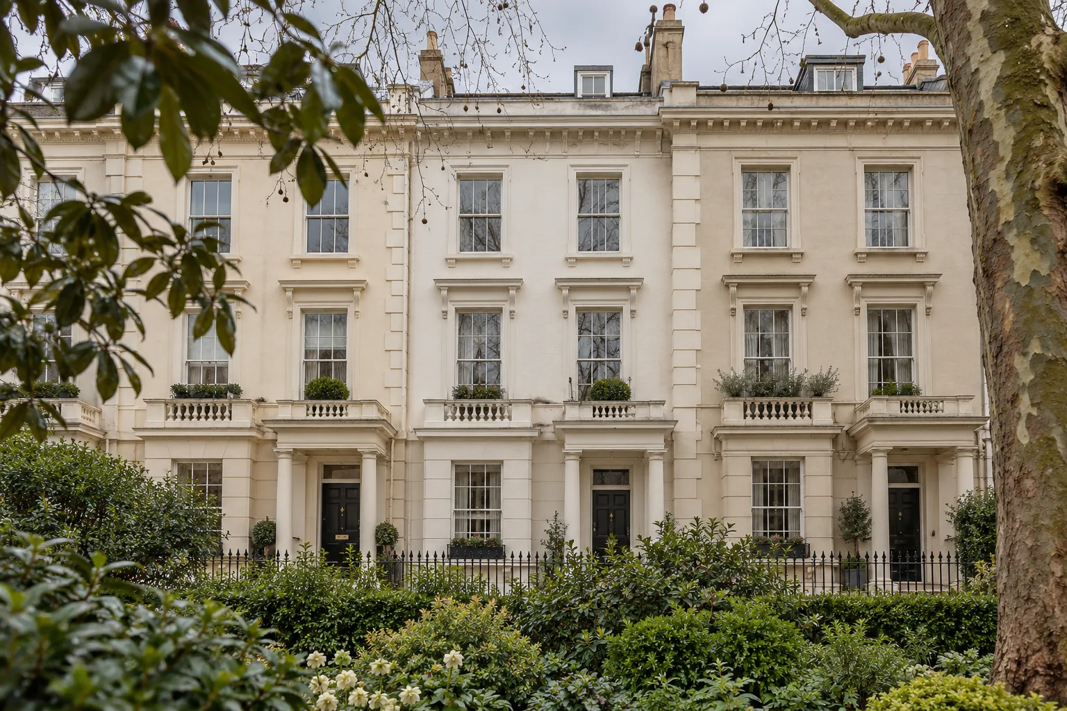 Cream stucco terrace overlooking a garden behind iron railings